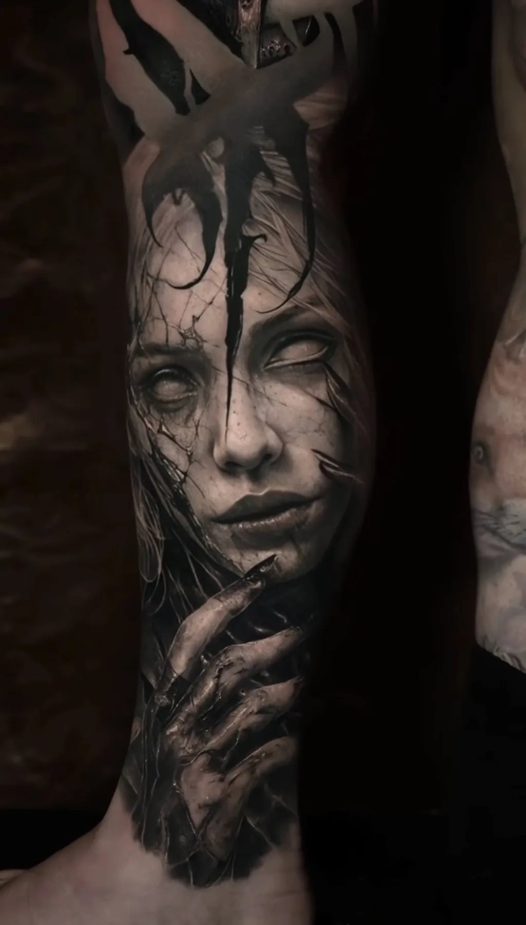 A fractured female portrait tattoo with a hand resting beneath the face.