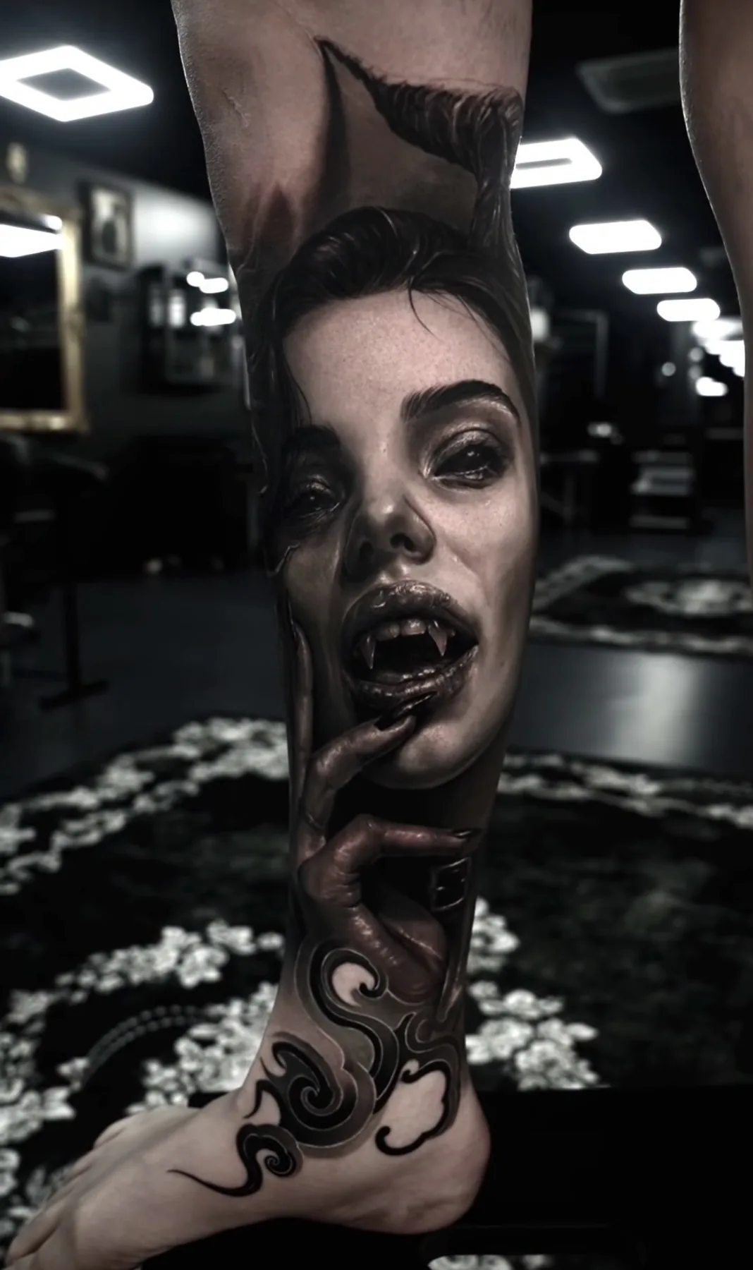 A black and grey portrait with fangs and ornamental shapes along the lower leg.