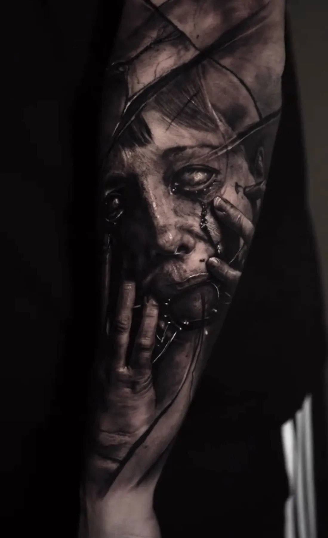 A fragmented female face with a hand and dark layered textures in a tattoo.
