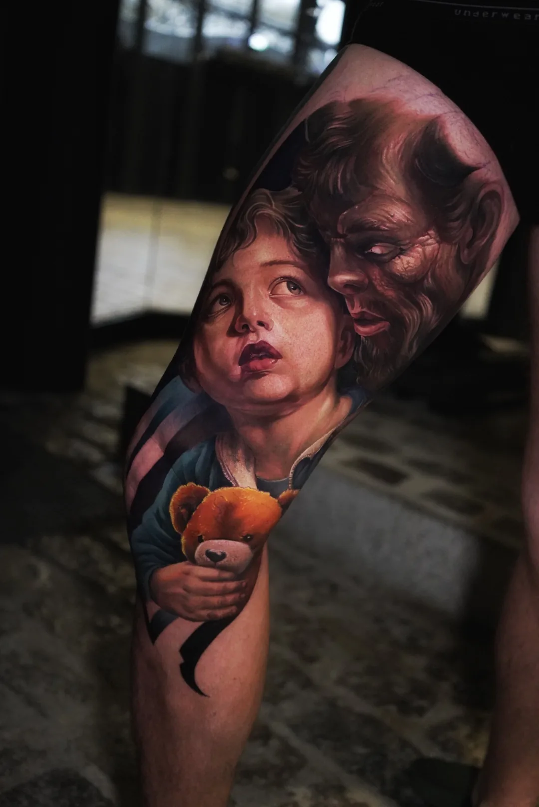 A child holding a teddy bear beneath a horned figure.