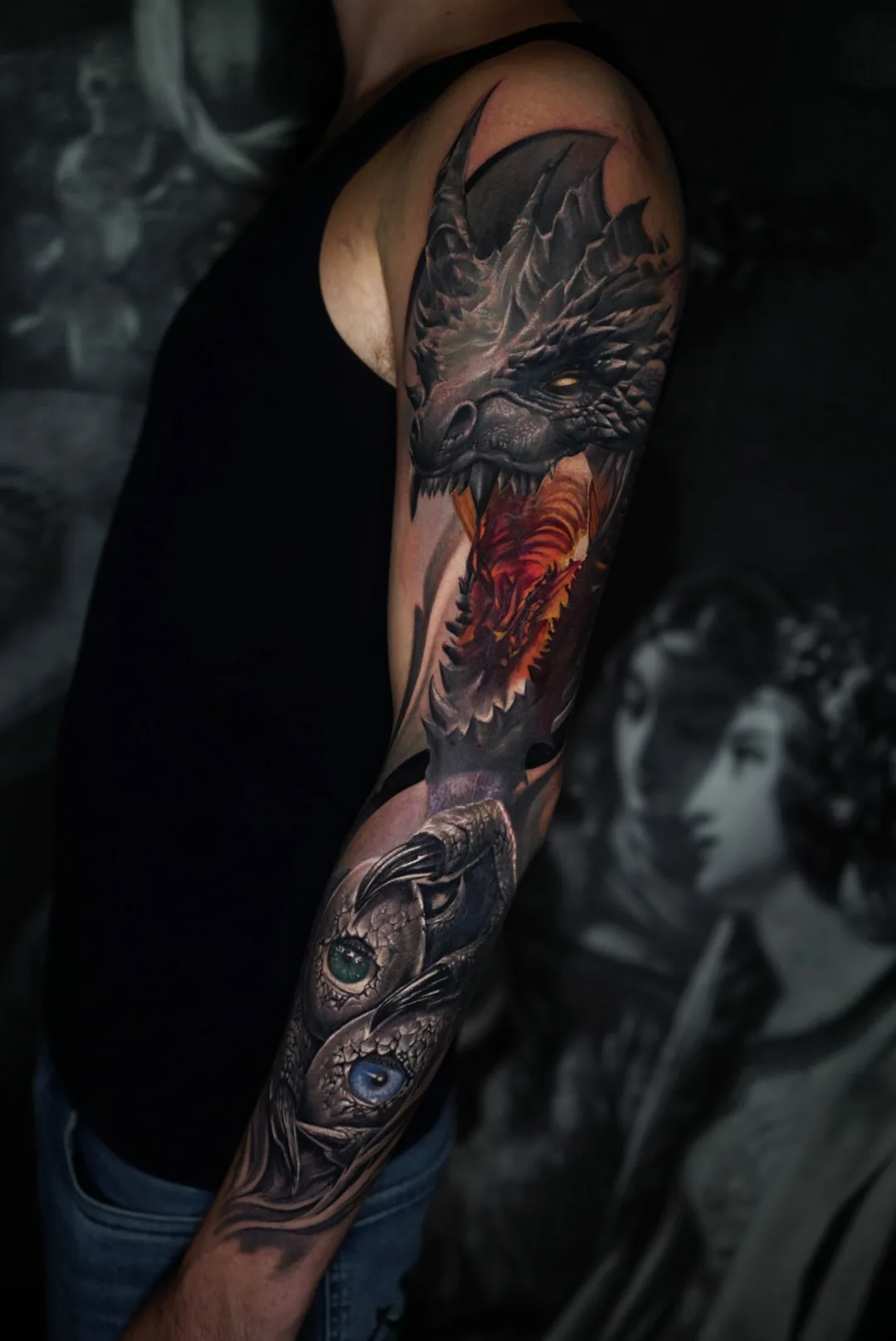 A dragon with fiery red accents in a detailed full-arm tattoo.