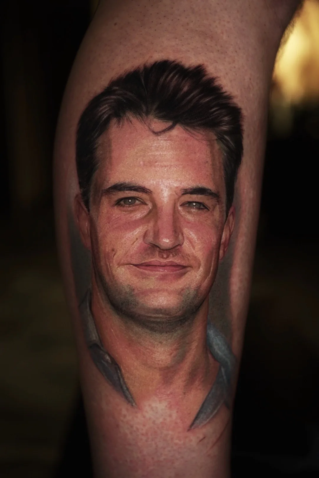 A lifelike male portrait tattoo with warm skin tones.