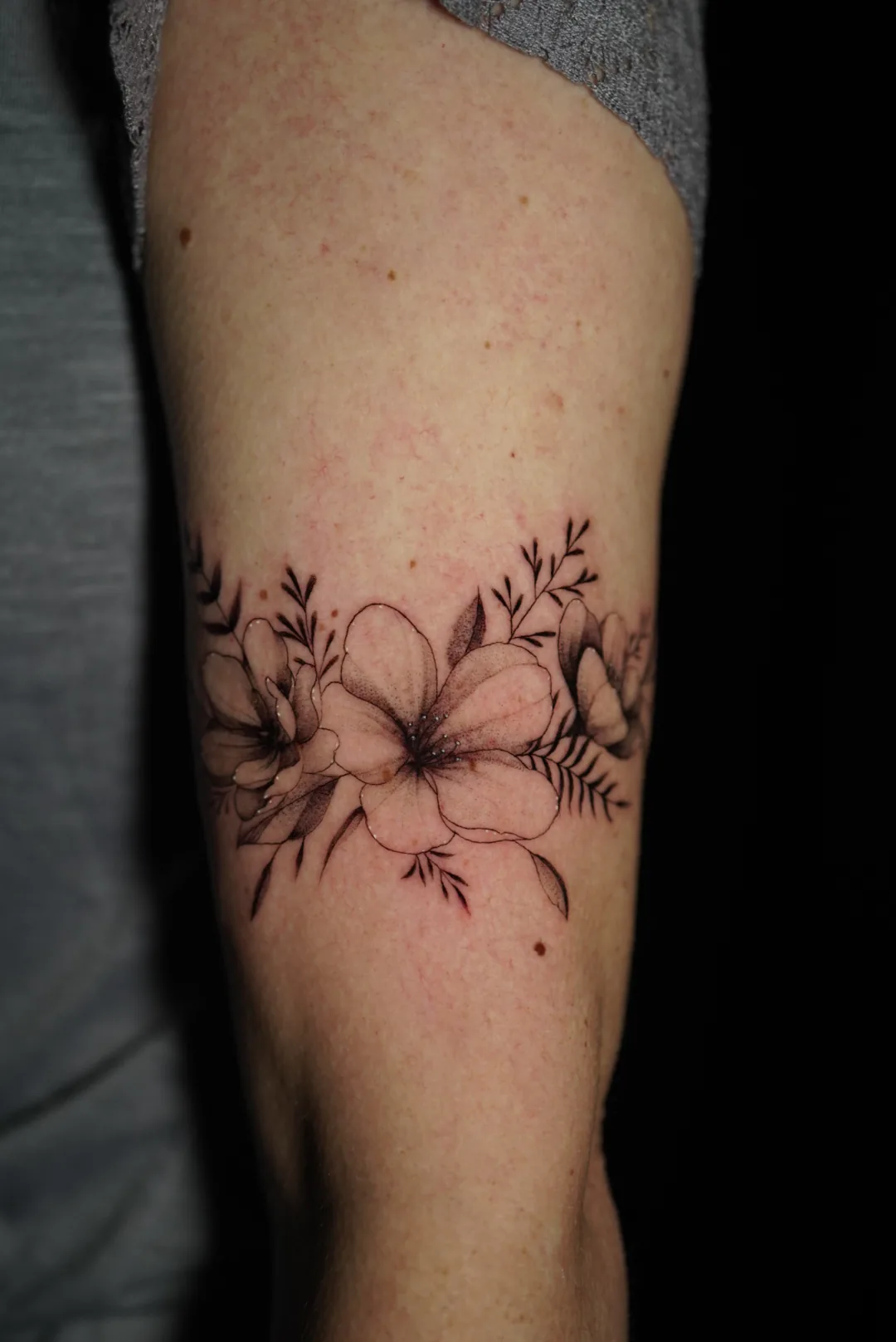 A fine-line floral bracelet around an arm.