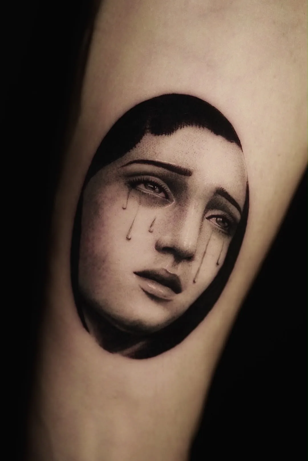 A micro-realism portrait of a weeping Virgin Mary in an oval, with tears on her cheeks.